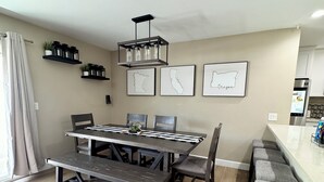 Een eetruimte met een houten tafel, bankjes en een hangende lamp.