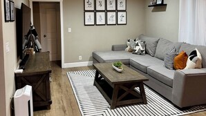 Een woonkamer met een bank, salontafel en ingelijste foto's aan de muur.