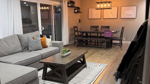 Een moderne woonkamer met een bank, salontafel en eethoek.