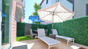 Un patio con dos sillones, una mesa y un paraguas azul.
