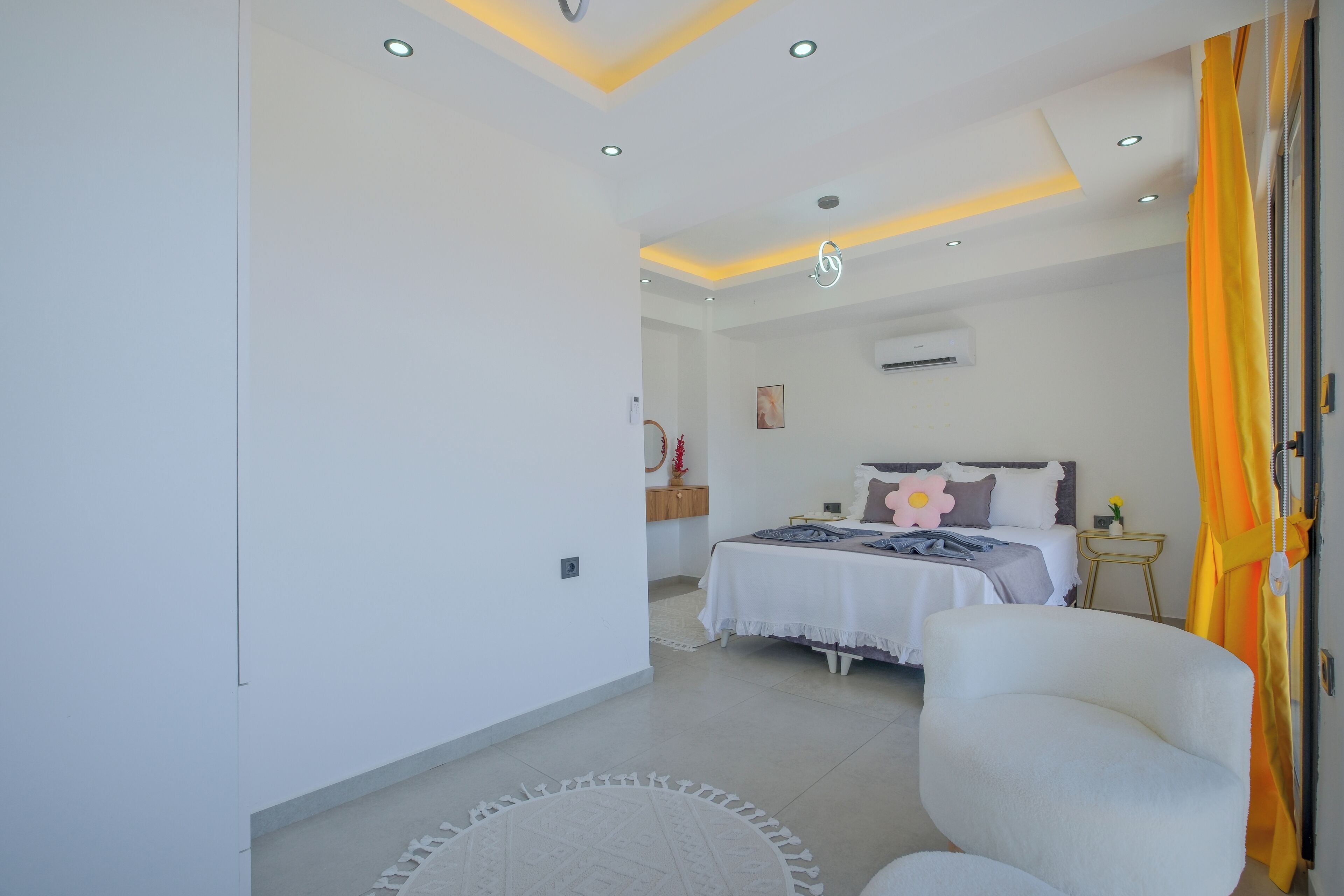 Une chambre à coucher comprenant un lit, une chaise, une table de chevet et un climatiseur fixé au mur.