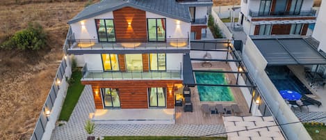 Une maison moderne à deux étages, dotée d’une piscine, d’un espace extérieur aménagé et d’un jardin bien entretenu.