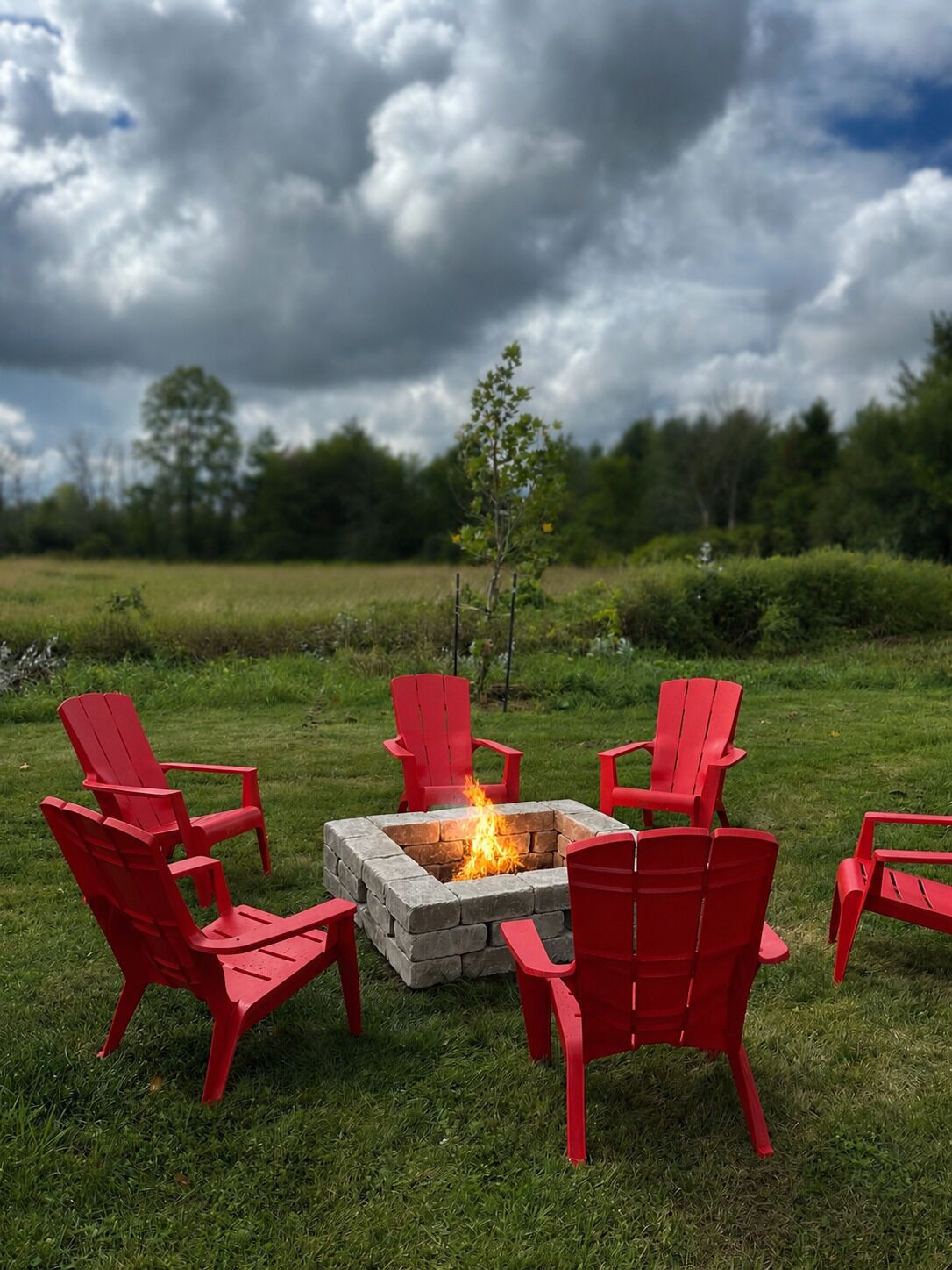 A fire pit with red chairs arranged around it in an outdoor setting.