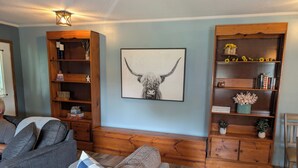 En stue med en sofa, en reol i træ og et indrammet kunstværk.