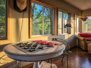 Une pièce avec une table ronde, une chaise, un canapé et une fenêtre donnant sur des arbres.