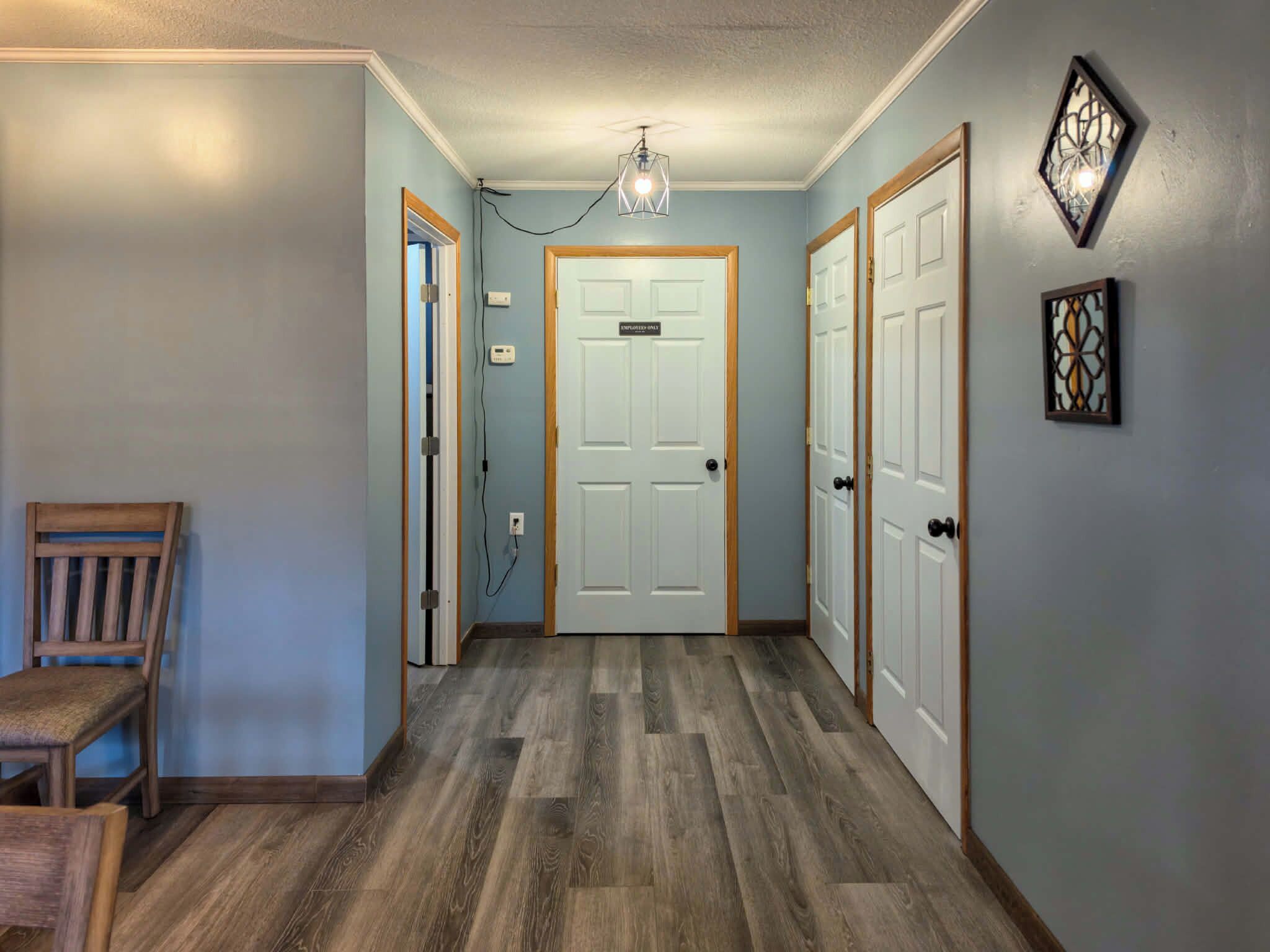 A hallway with a wooden floor, a door labeled 'EMPLOYEE ONLY,' and a chair on the left.