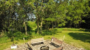 An outdoor seating area with a fire pit, benches, and a paved ground.