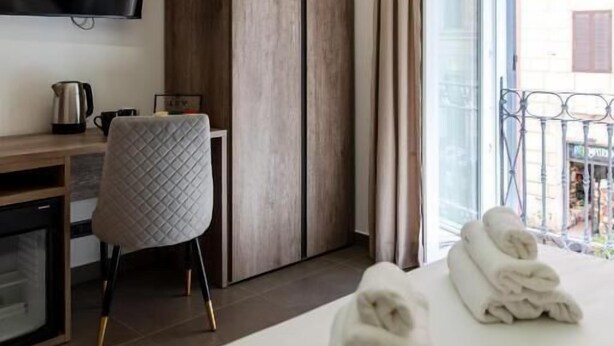 A hotel room with a bed, a desk, a chair, a television, and a balcony.