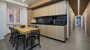 A modern kitchen with a wooden island, black appliances, and a dining area with chairs and a table.