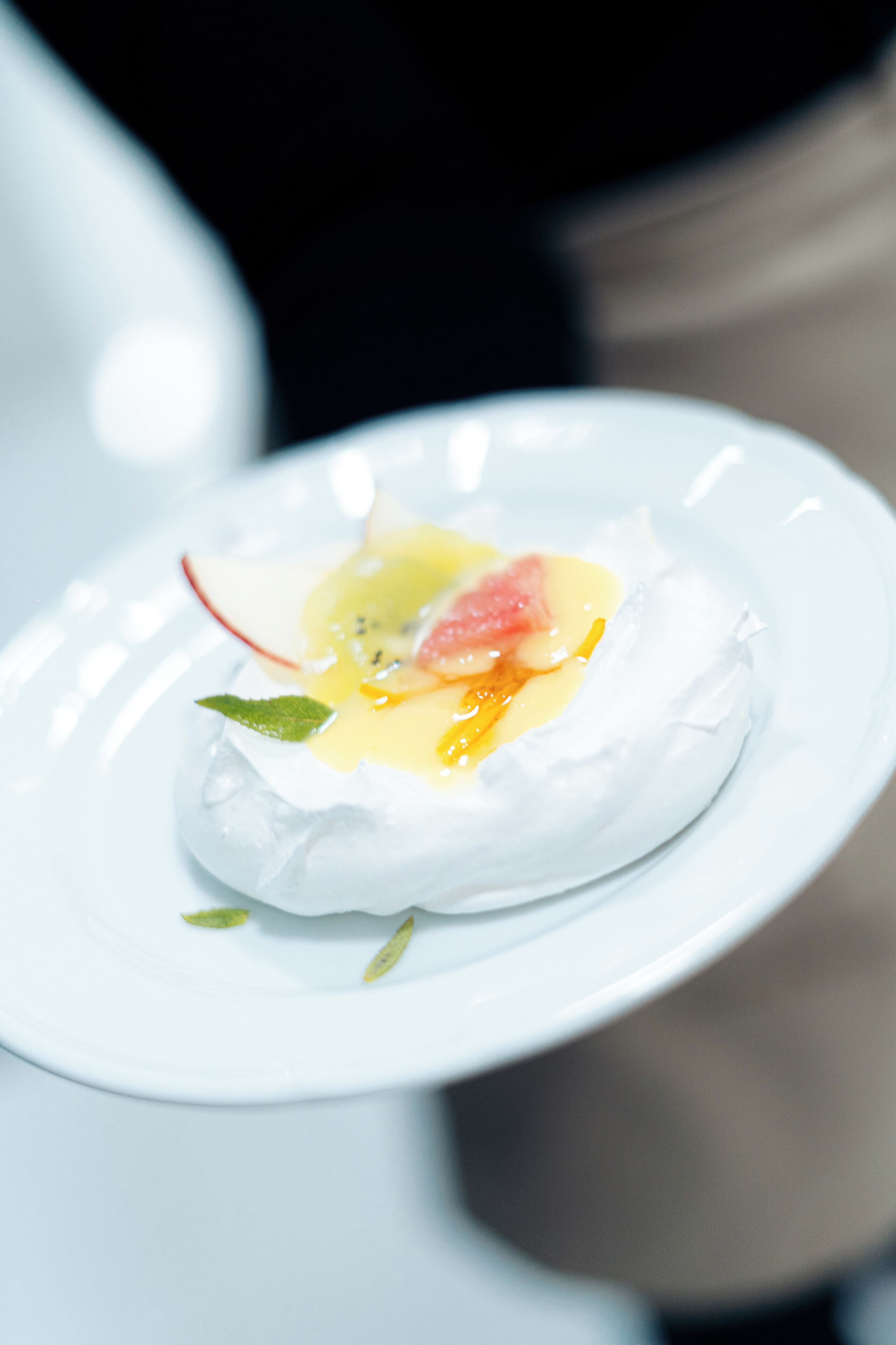 A white plate with a dessert on a reflective surface.