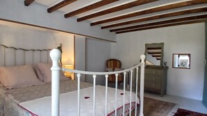 Un dormitorio con cama, mesita de noche, cómoda y espejo.