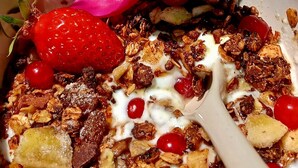 Un tazón de cereal con fresas, yogur y granola.