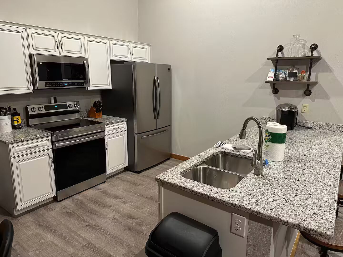 A modern kitchen with stainless steel appliances, a granite countertop, and a built-in oven.