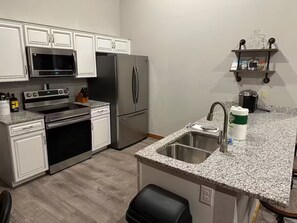 Eine moderne Küche mit Edelstahlgeräten, einer Granitarbeitsplatte und einem eingebauten Backofen.
