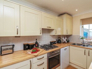 A kitchen with white cabinets, a wooden countertop, a gas stove, a built-in oven, and a sink. - Overcarr Cottage (Malton)