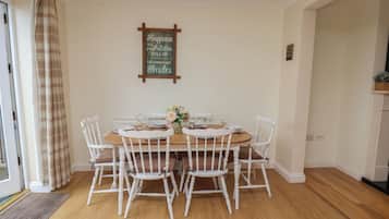 A dining area with a wooden table, white chairs, and a sign on the wall.