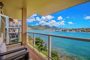Un balcon offrant une vue sur une mer turquoise et des montagnes lointaines.