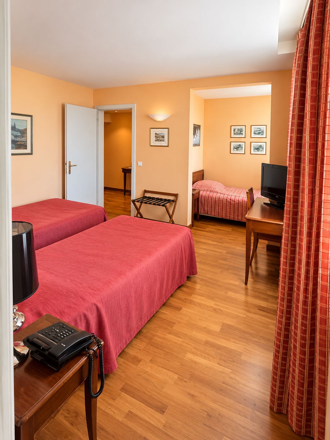 Een hotelkamer met twee bedden, een bureau met een computer, een telefoon en een stoel.