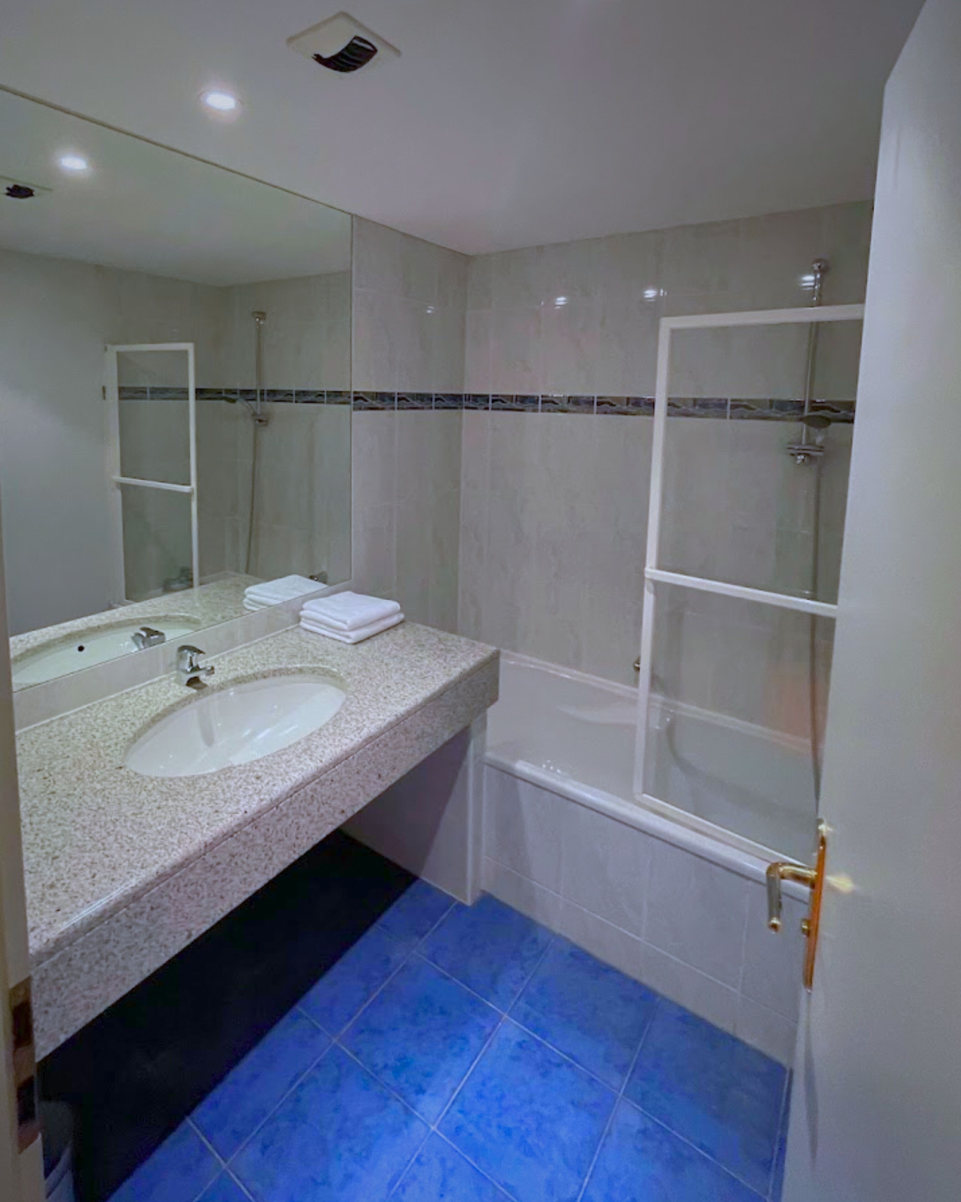 A bathroom with a sink, mirror, and shower.
