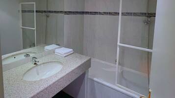 A bathroom with a sink, mirror, and shower.