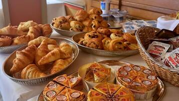A buffet table with various baked goods and cheeses.