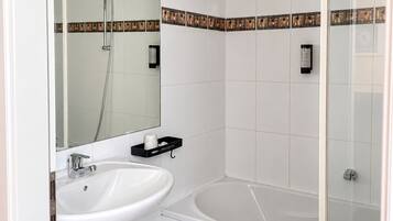 Un baño con lavamanos blanco, espejo, ducha y bañera.