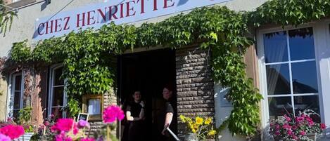 Un restaurante llamado 'Chez Henriette' con terraza y un letrero que indica que es un bistró.