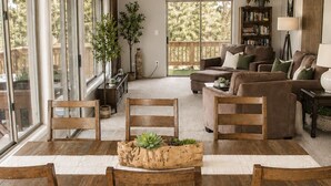 Un salón amplio con una gran mesa de comedor, diversas opciones de asiento y un ventanal con vistas al exterior.