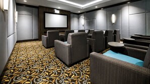 Una sala cinema moderna con sedute confortevoli, uno schermo grande e un tappeto decorato.
