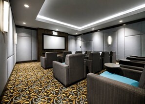 A modern cinema room with plush seating, a large screen, and a patterned carpet.