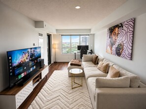 A living room with a TV, sofa, coffee table, and artwork.