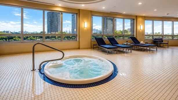 Un'area benessere con vasca idromassaggio, poltrone relax e ampie finestre con vista sulla città.