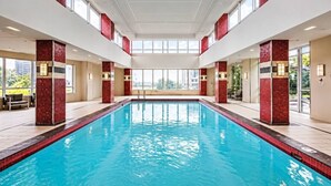 Un'ampia piscina coperta con pareti in piastrelle rosse e un soffitto alto.