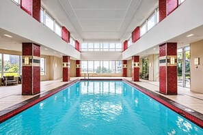 A large indoor swimming pool with red-tiled walls and a high ceiling.