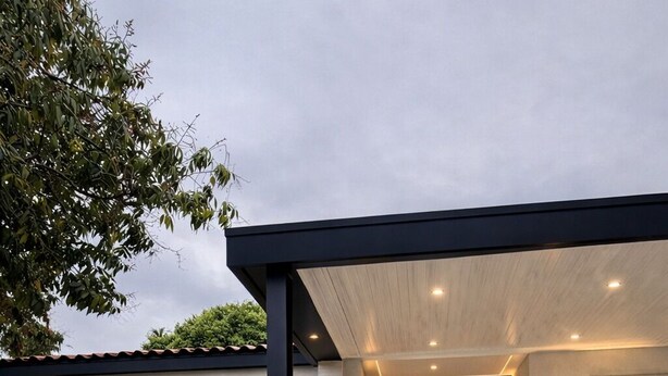 A modern house with a paved entrance, a dark front door, and a well-lit pathway. - 5640 NE Miami (Miami)