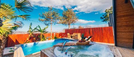A backyard with a swimming pool, a hot tub, and a wooden deck.