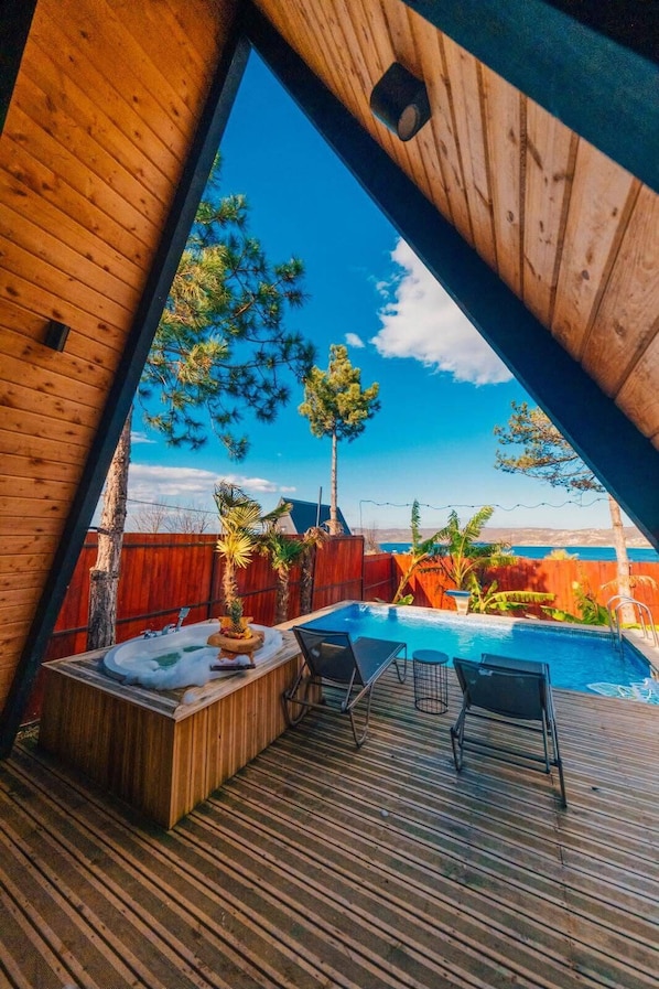 Um deck de madeira com piscina, espreguiçadeiras e vista para o oceano.