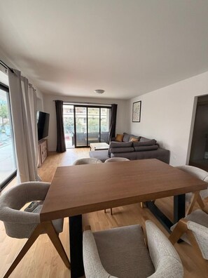 A modern living room with a wooden dining table, grey sofas, and a TV. - Alimos Urban Retreat (Alimos)