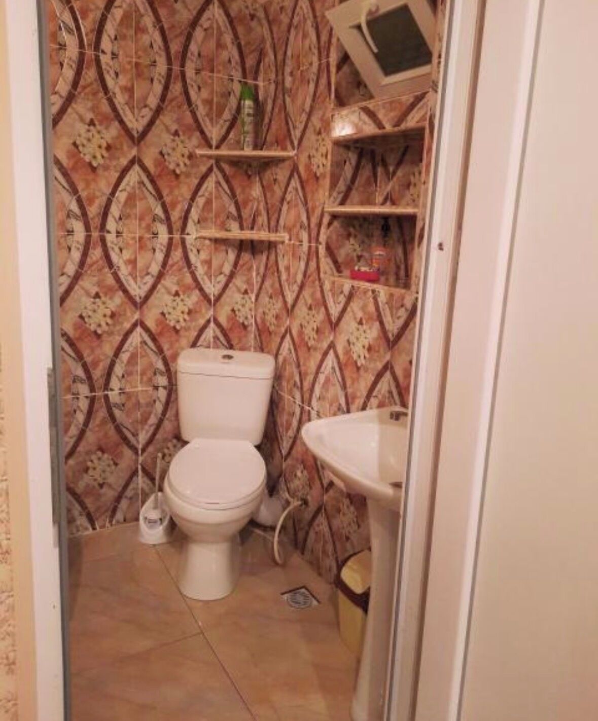 Baño con inodoro, lavamanos y azulejos con diseño.