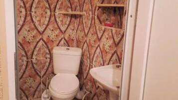 Baño con inodoro, lavamanos y azulejos con diseño.