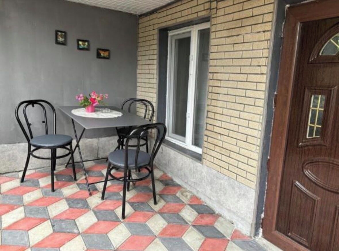 Een terras met een tafel, stoelen, een raam en een deur.