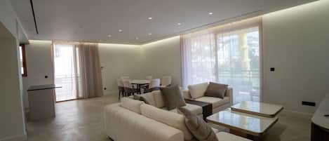 A modern living room with a sofa, coffee table, and dining area.