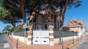 En historisk byggnad med en grind vid ingången, en fasad av tegel och traditionell arkitektur.