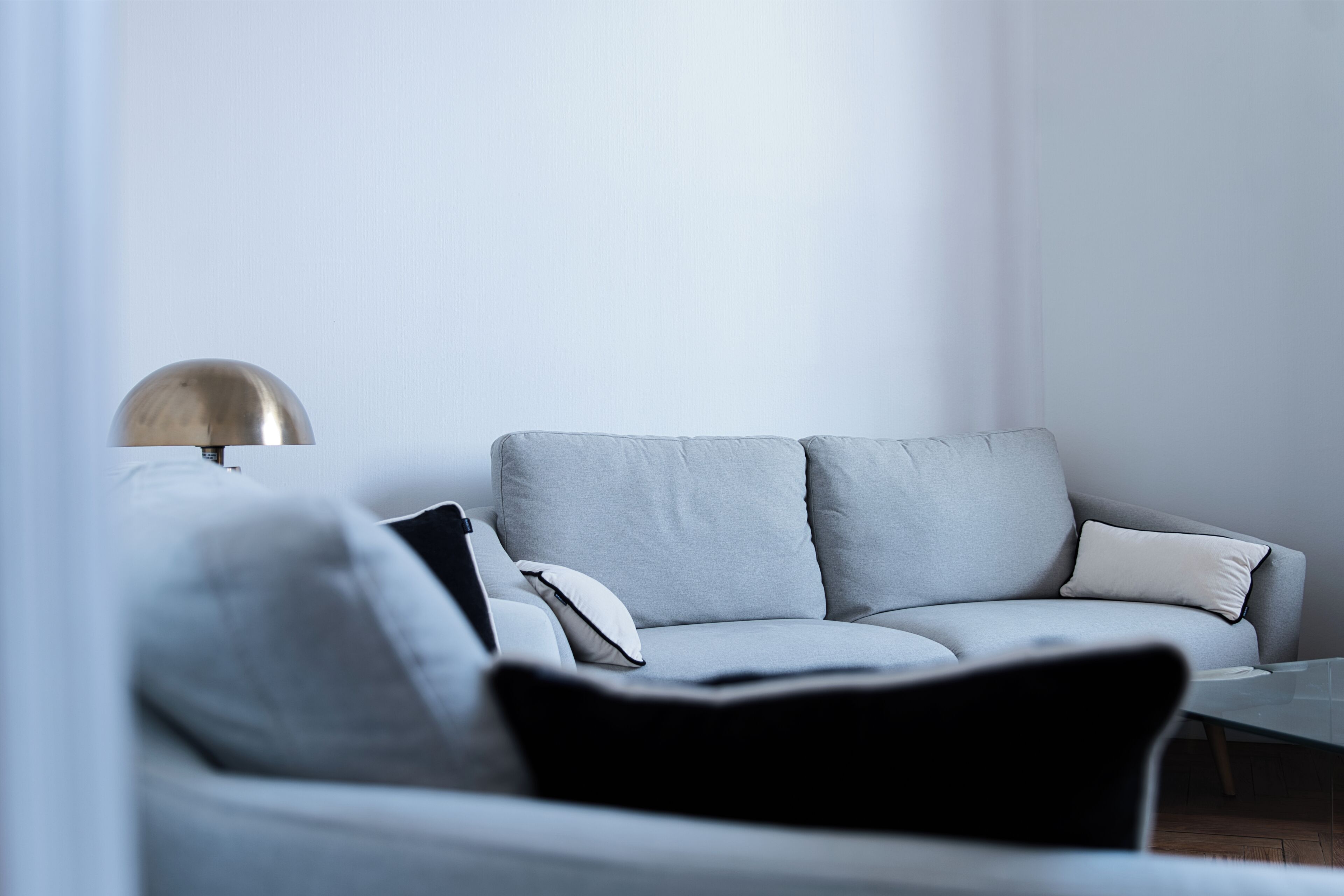 A modern living room with a grey sofa, a glass coffee table, and a floor lamp.