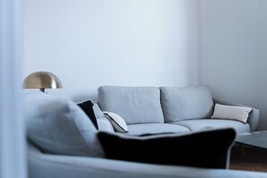 A modern living room with a grey sofa, a glass coffee table, and a floor lamp. - Villa Le Cid *Charm, Elegance, and the Beaches of Soulac* (Soulac-sur-Mer)