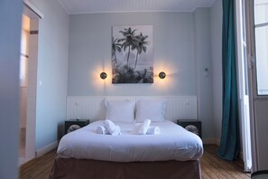A hotel room with a bed, two bedside tables, a wall-mounted picture, and a window with curtains. - Villa Le Cid *Charm, Elegance, and the Beaches of Soulac* (Soulac-sur-Mer)