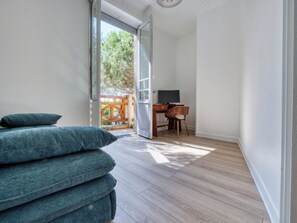 A room with a bed, a desk with a chair, and a television. - Villa Le Cid *Charm, Elegance, and the Beaches of Soulac* (Soulac-sur-Mer)