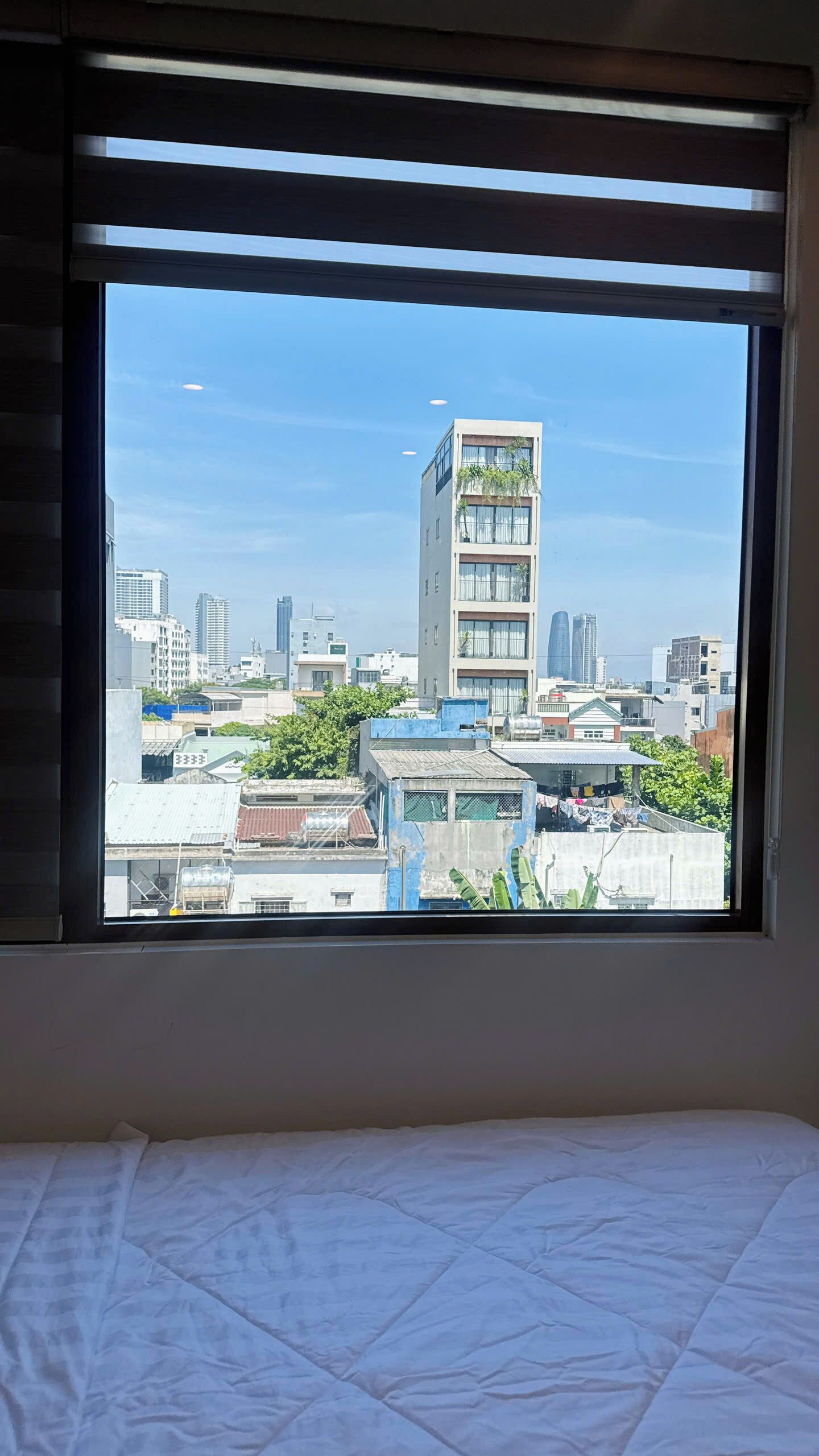 Quarto com cama e janela com vista para a cidade.