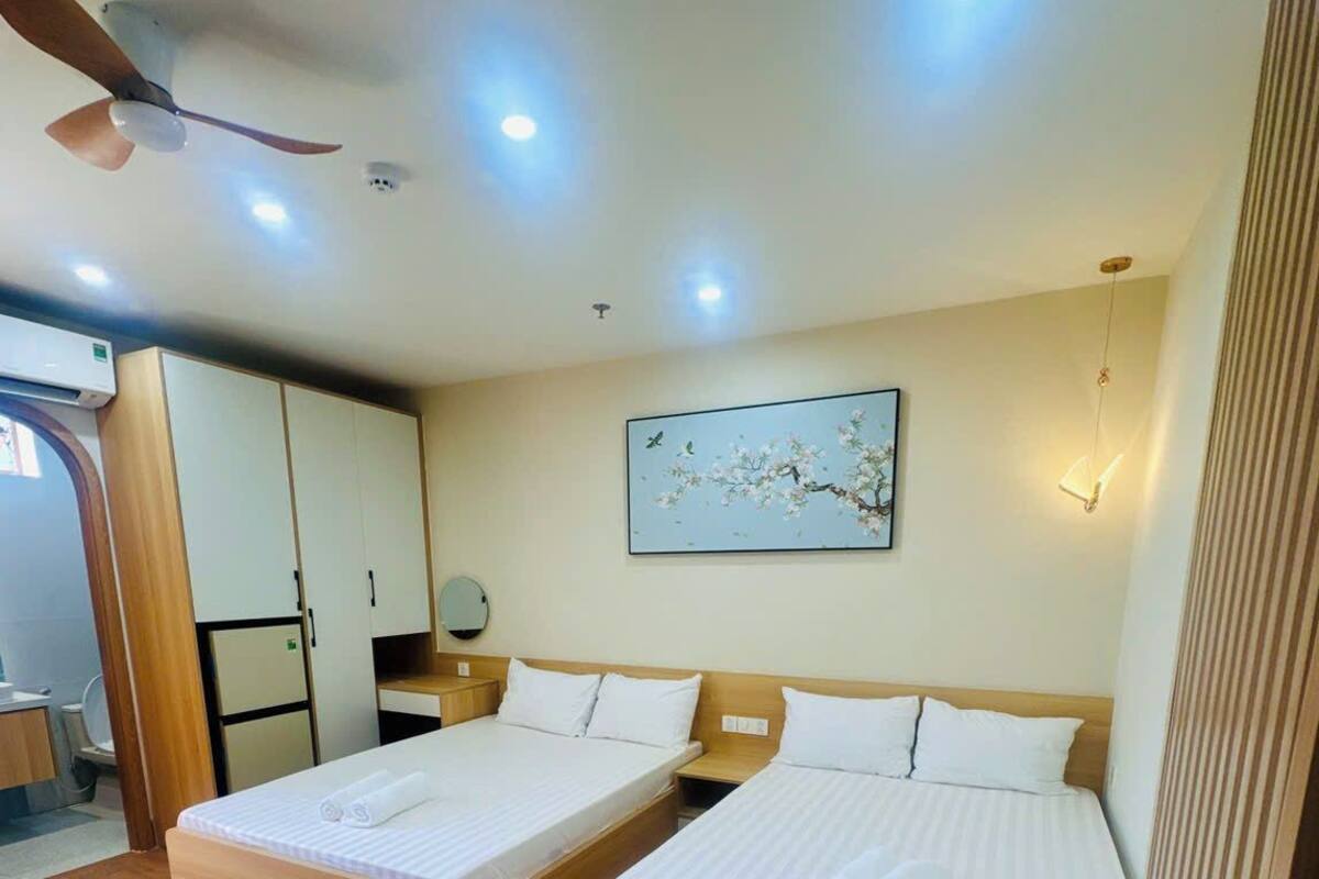 A hotel room with two beds, a ceiling fan, recessed lighting, a wall-mounted artwork, and a wooden floor.