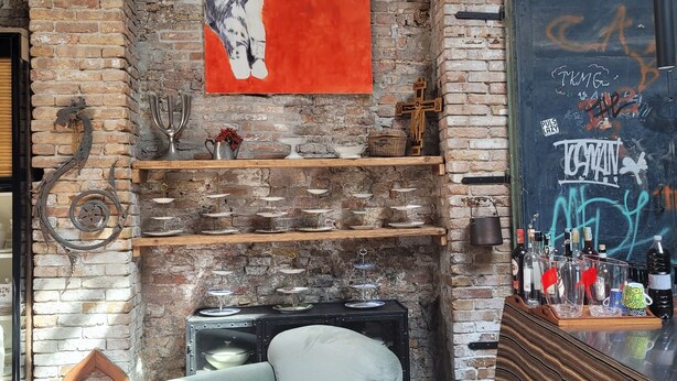 Une pièce aux murs en briques apparentes, avec une cheminée, un coin bar et un grand tableau représentant un chat.